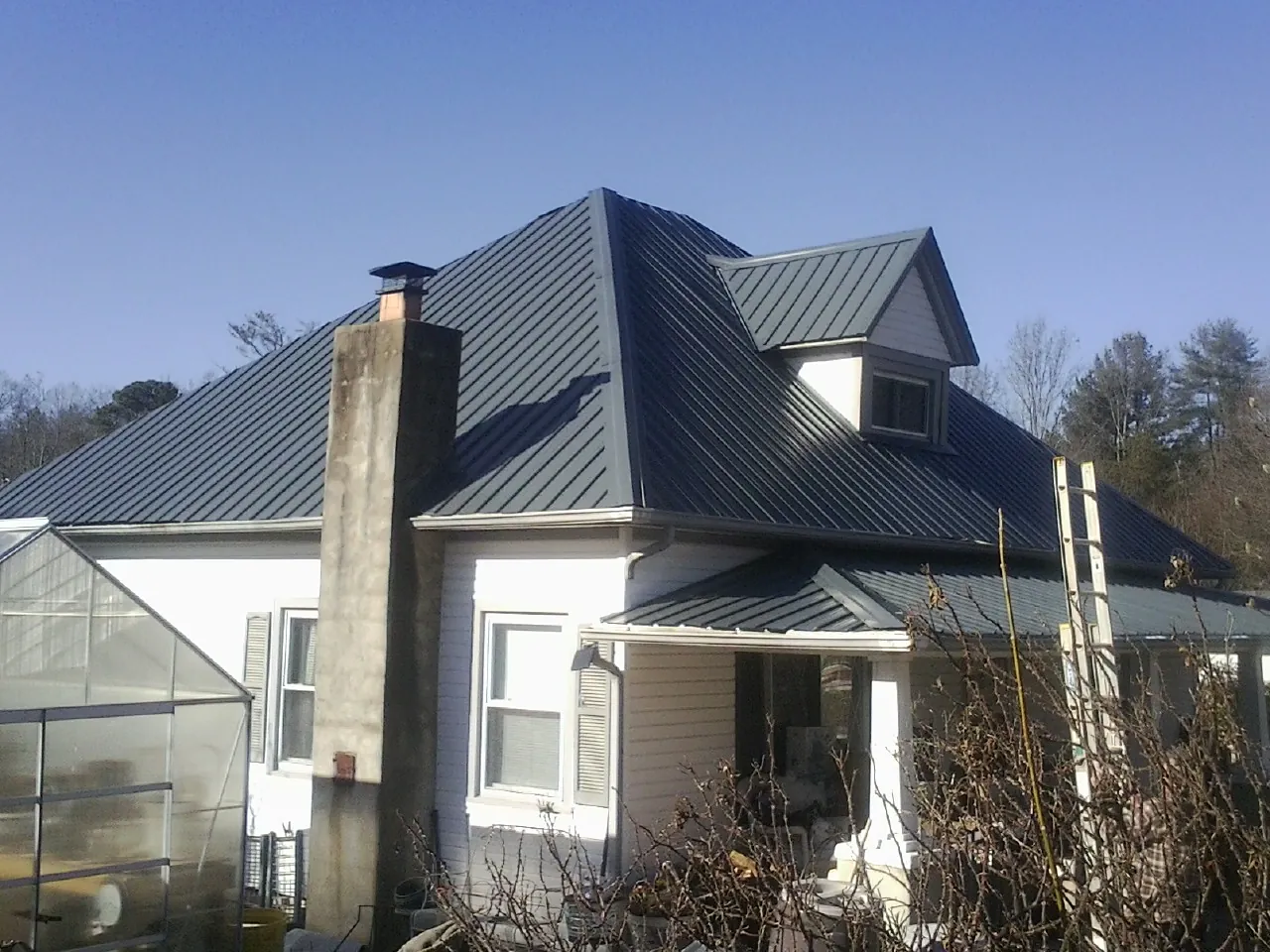 Dark blue standing seam metal roof on a white farmhouse with dormer — Slate & Tile Roof Repair by Roofing Brothers in Port Ludlow