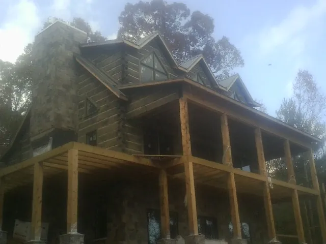 Stone chimney and dormers on a large log home with a timber porch in Port Ludlow