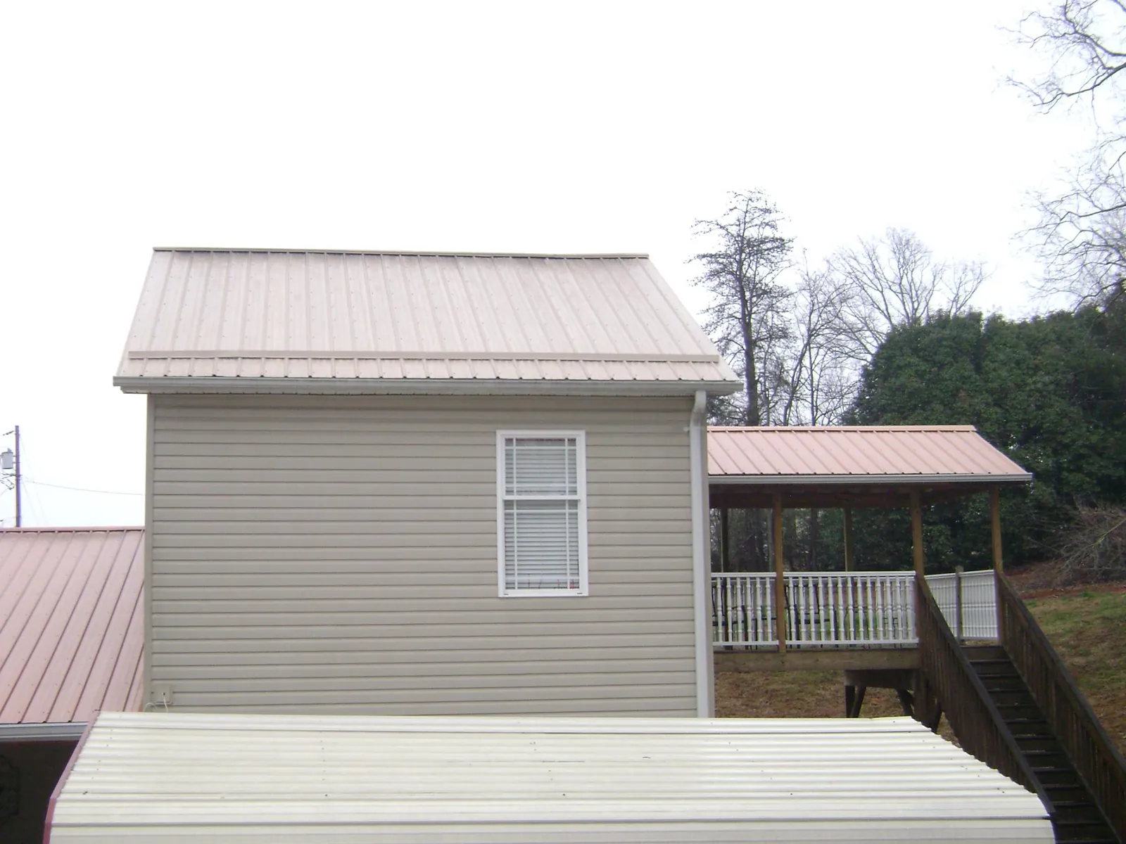Tan metal roofs on a two story addition and attached porch, from a Roof Replacement job in Port Ludlow