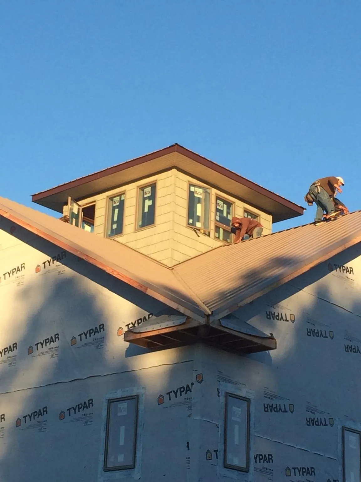 Roofers working around a rooftop cupola on a new metal roof at sunset — Roof Waterproofing in Port Ludlow by Roofing Brothers